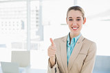 Cheerful classy businesswoman showing thumbs up smiling at camera