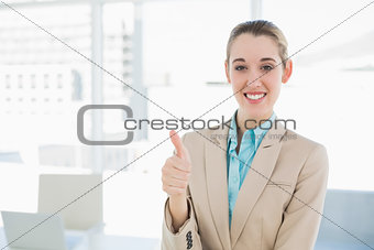 Cheerful classy businesswoman showing thumbs up smiling at camera