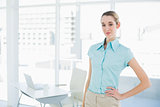 Attractive calm businesswoman posing in her office with hand on hip