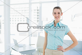Cheerful attractive businesswoman posing with hand on hip