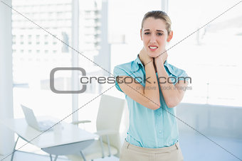 Beautiful suffering businesswoman touching her injured neck