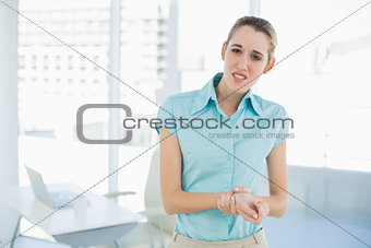 Beautiful young businesswoman gripping her injured wrist