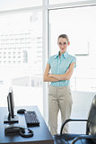 Calm serious businesswoman posing with arms crossed standing in her office
