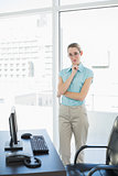 Calm businesswoman standing thoughtful in her office