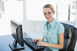 Beautiful calm businesswoman working on her computer smiling at camera