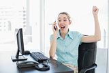 Gorgeous businesswoman cheering while phoning with her smartphone