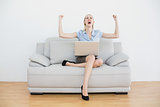 Cheering beautiful businesswoman sitting on her couch in her office