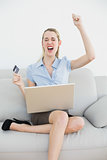 Attractive cheering businesswoman online shopping with her laptop