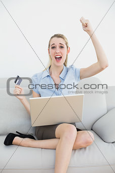 Happy classy businesswoman online shopping using her notebook