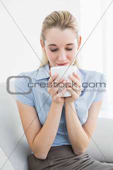 Relaxed calm businesswoman holding a cup smelling it
