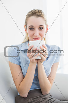 Gorgeous calm businesswoman holding a cup smelling a cup