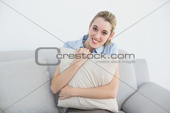 Content peaceful businesswoman sitting on couch holding a pillow