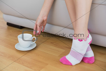 Young slim woman wearing pink socks reaching for a cup