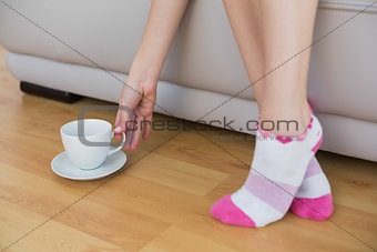 Slender woman wearing pink socks reaching for a cup