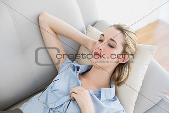 Calm blonde businesswoman lying sleeping on her couch