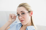 Calm serious businesswoman sitting on couch wearing glasses