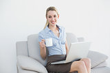 Content lovely businesswoman using her notebook holding a cup