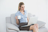 Lovely calm businesswoman using her notebook holding a cup