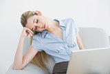 Exhausted ponytailed businesswoman sitting on couch sleeping