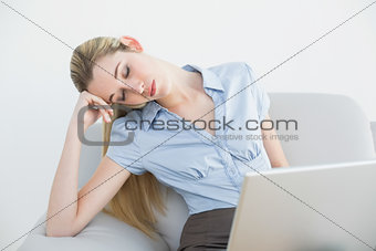 Exhausted ponytailed businesswoman sitting on couch sleeping