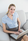 Beautiful smiling businesswoman using her notebook sitting on couch