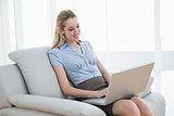 Cheerful classy businesswoman sitting on couch using her notebook