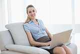Beautiful chic businesswoman using her notebook sitting on couch
