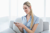 Cute businesswoman texting with her smartphone sitting on couch