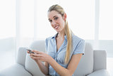 Beautiful content businesswoman texting with her smartphone sitting on couch