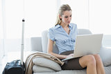 Concentrated blonde businesswoman working on her notebook sitting on couch