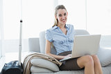 Cute businesswoman using her notebook sitting on couch