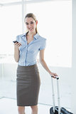 Cute businesswoman standing in her office holding her smartphone