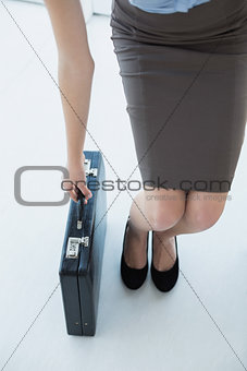 Young chic businesswoman taking her black briefcase