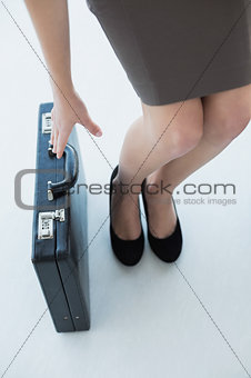 Chic businesswoman reaching for her black briefcase