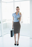 Young classy businesswoman posing holding a briefcase and newspaper