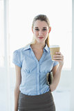 Attractive classy businesswoman posing holding a disposable cup and newspaper