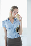 Content chic businesswoman drinking of disposable cup holding a newspaper