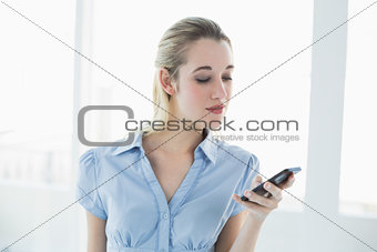 Serious classy businesswoman messaging with her smartphone