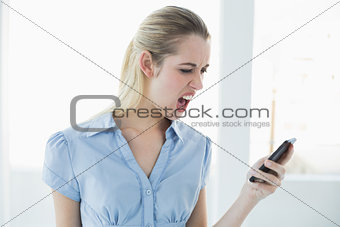 Shocked classy businesswoman using her smartphone