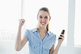Cheering chic businesswoman holding her smartphone