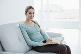 Beautiful casual woman sitting on couch reading a book