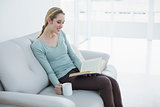 Attractive blonde woman relaxing reading a book holding a cup