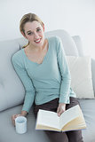 Attractive casual woman sitting on couch while reading a book