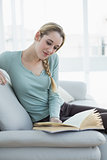 Content calm woman reading a book while sitting on couch