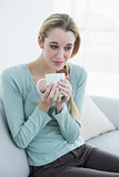 Gorgeous relaxing woman sitting on couch holding a cup