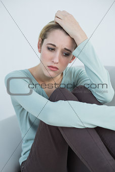 Attractive thoughtful woman sitting on couch