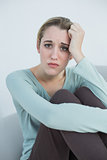 Natural young woman sitting worried on couch