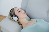 Casual blonde woman listening to music lying on couch