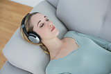 Peaceful natural woman listening to music while lying on couch