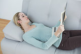 Slender natural woman reading newspaper lying on couch